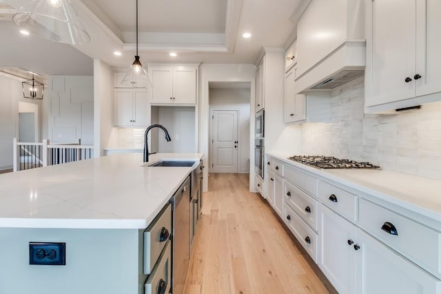 kitchen featuring custom range hood, stainless steel gas cooktop, sink, pendant lighting, and white cabinets