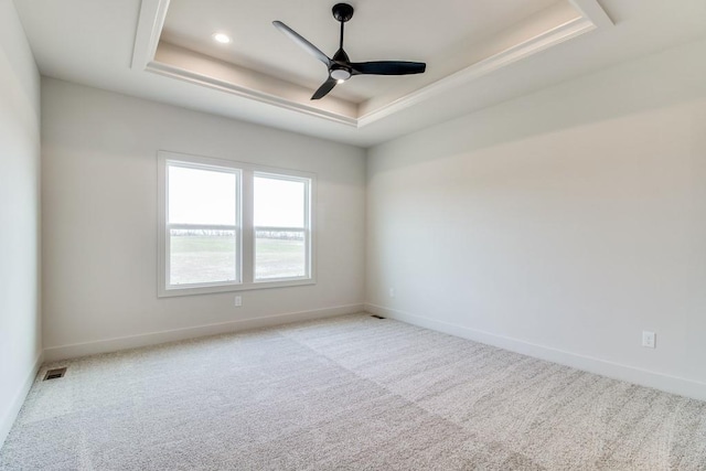 carpeted empty room featuring a tray ceiling and ceiling fan