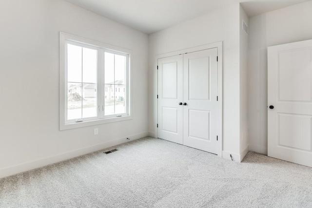 unfurnished bedroom with a closet and light colored carpet