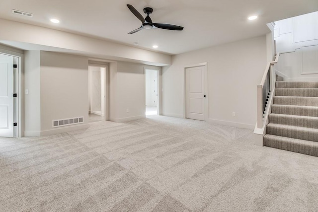 basement with ceiling fan and light colored carpet