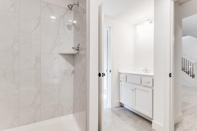 bathroom with a tile shower and vanity