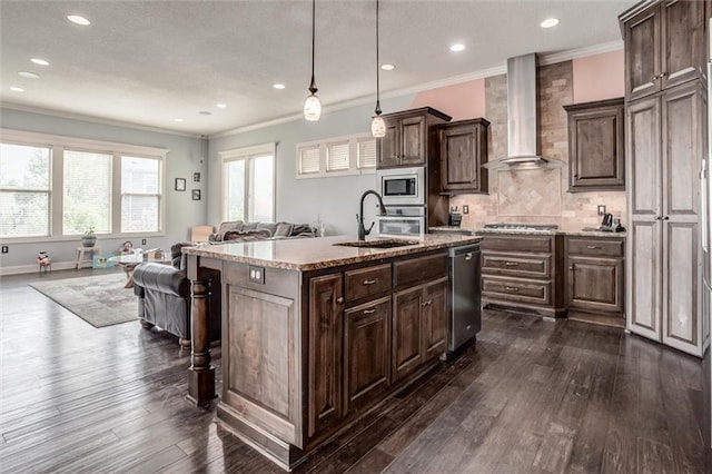 kitchen featuring stainless steel appliances, wall chimney exhaust hood, dark wood-type flooring, a center island with sink, and dark brown cabinets