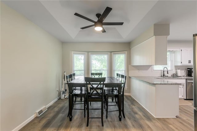 dining space with a tray ceiling, sink, ceiling fan, and hardwood / wood-style floors