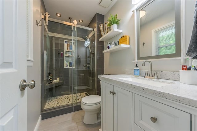 bathroom featuring tile patterned floors, a shower with door, toilet, and vanity