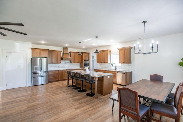 dining space with sink, light wood-type flooring, and ceiling fan with notable chandelier