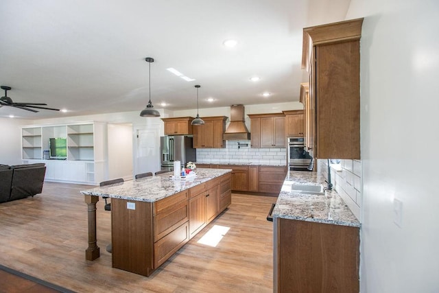 kitchen featuring custom exhaust hood, ceiling fan, tasteful backsplash, a kitchen island, and a breakfast bar