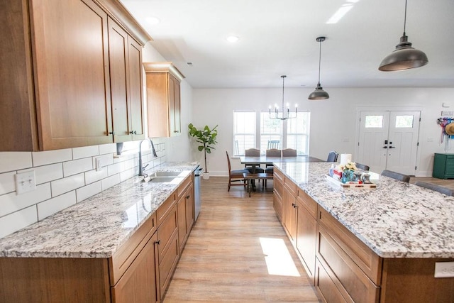 kitchen with light hardwood / wood-style flooring, sink, backsplash, decorative light fixtures, and a center island