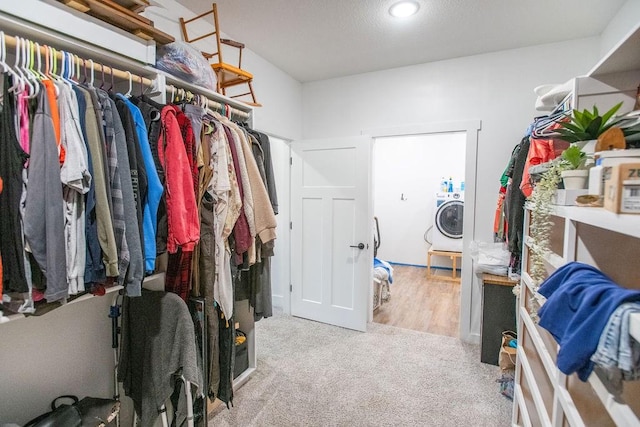 spacious closet featuring washer / clothes dryer and light carpet