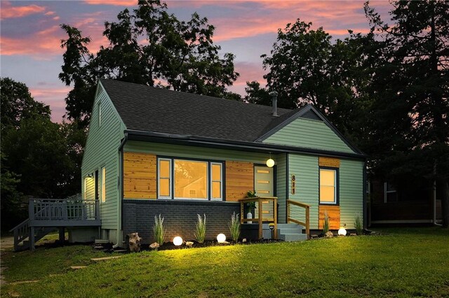 back house at dusk featuring cooling unit, a lawn, and a deck