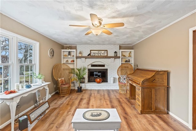 sitting room featuring a brick fireplace, ceiling fan, crown molding, and light hardwood / wood-style flooring