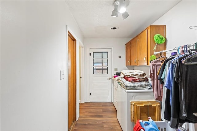 clothes washing area featuring washer and clothes dryer, cabinets, dark hardwood / wood-style floors, ceiling fan, and a textured ceiling