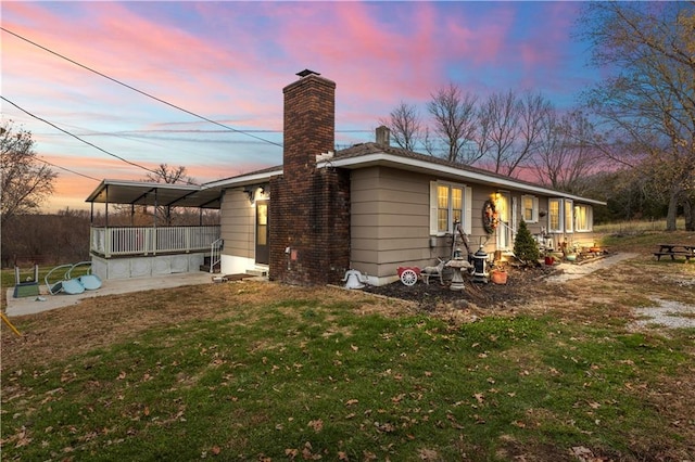 back house at dusk featuring a yard and a porch