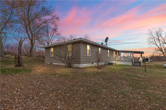 property exterior at dusk with a yard and central AC