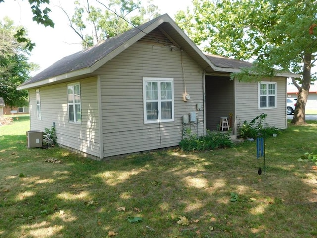 back of property with central AC unit and a lawn