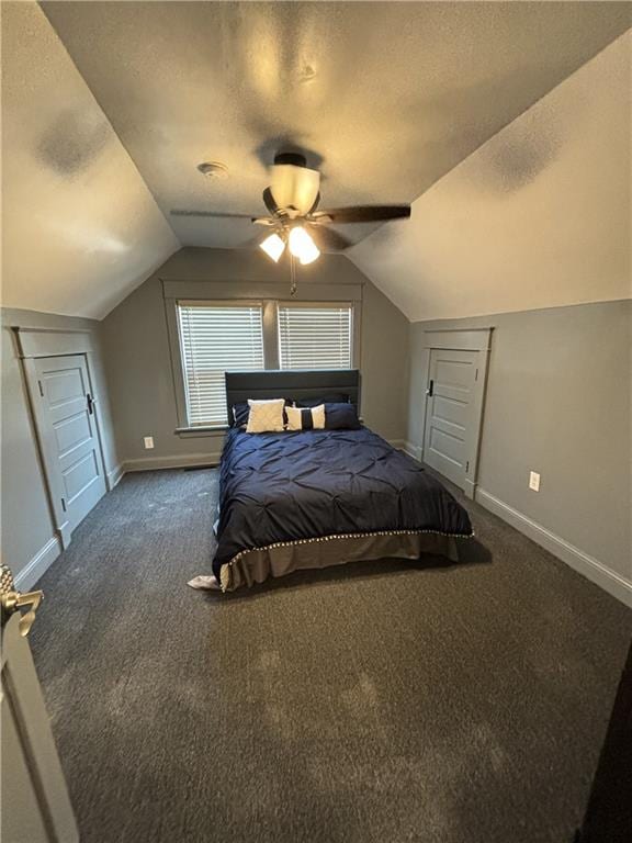 bedroom with vaulted ceiling, dark colored carpet, and a textured ceiling