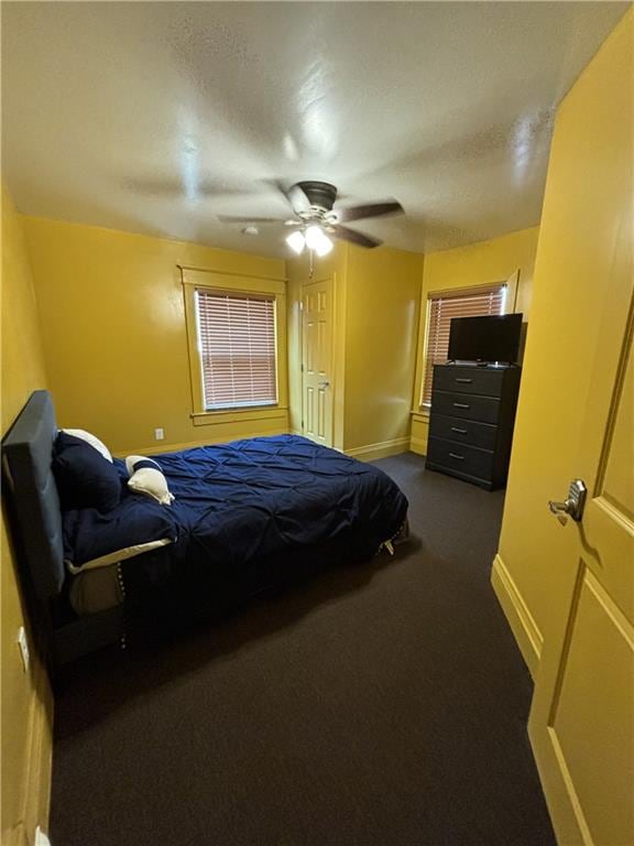 bedroom with dark carpet, a ceiling fan, and baseboards