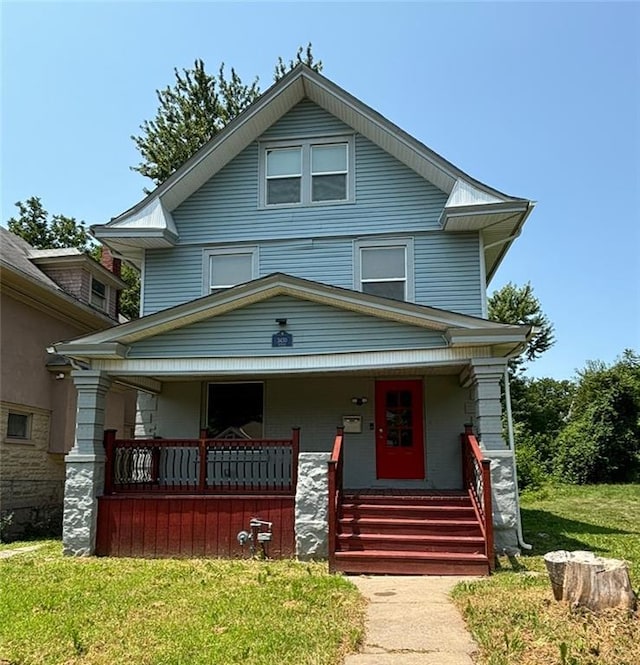 american foursquare style home with a front lawn and covered porch