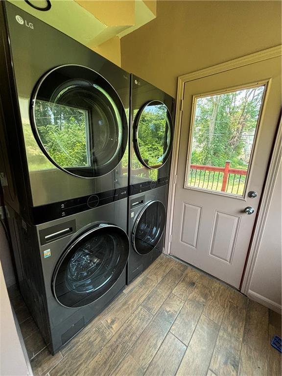 laundry room with wood finished floors, laundry area, and stacked washer / dryer