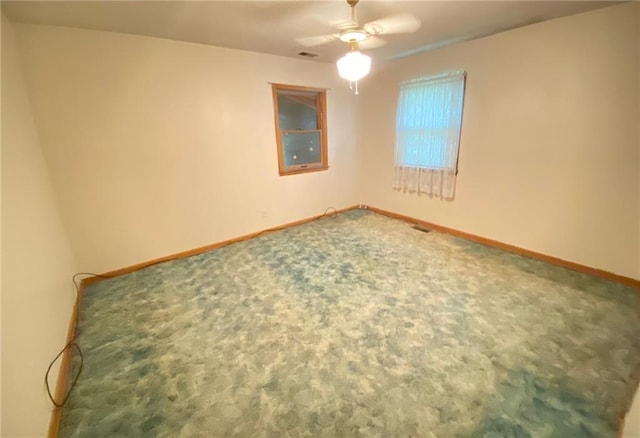 carpeted spare room with a ceiling fan, visible vents, and baseboards