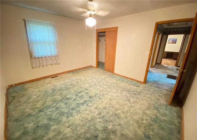 unfurnished bedroom featuring visible vents, ceiling fan, baseboards, carpet, and a closet