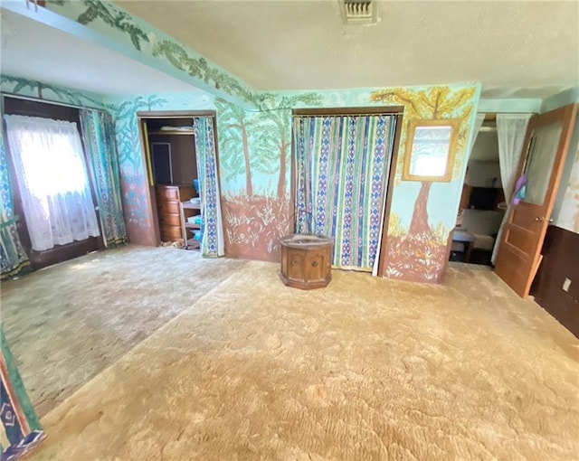 empty room with carpet flooring, wallpapered walls, and visible vents