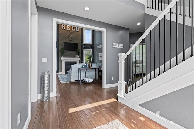 foyer with hardwood / wood-style flooring, a fireplace, and a high ceiling