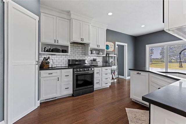 kitchen with sink, backsplash, stainless steel gas range, white cabinetry, and dark hardwood / wood-style flooring