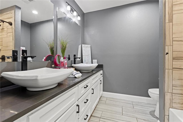 bathroom featuring tile patterned flooring, toilet, and double sink vanity