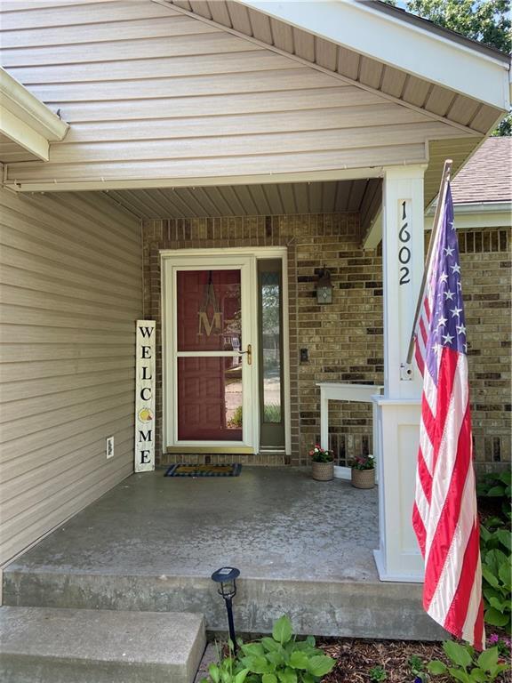 view of exterior entry featuring covered porch and brick siding