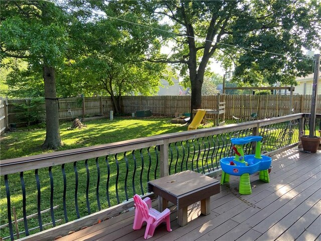 deck featuring a fenced backyard, a lawn, and a playground