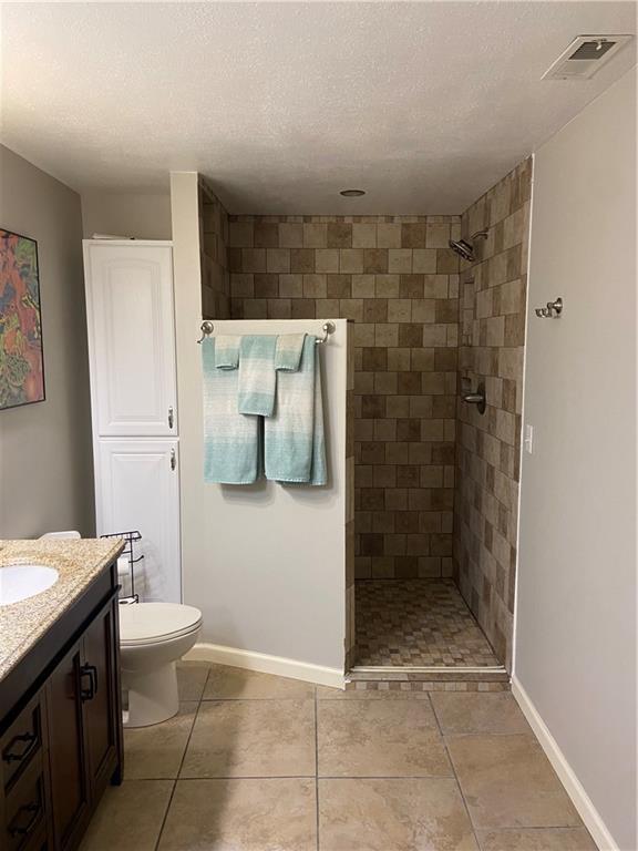 bathroom with baseboards, visible vents, vanity, and a textured ceiling