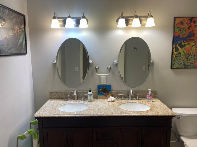 bathroom with a sink, toilet, and double vanity