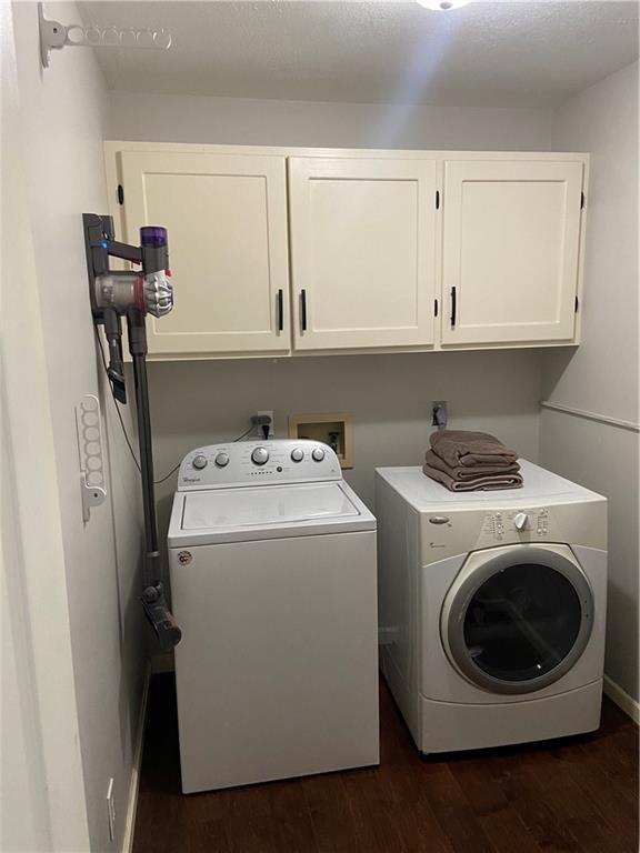 clothes washing area with cabinet space, dark wood-style flooring, and independent washer and dryer