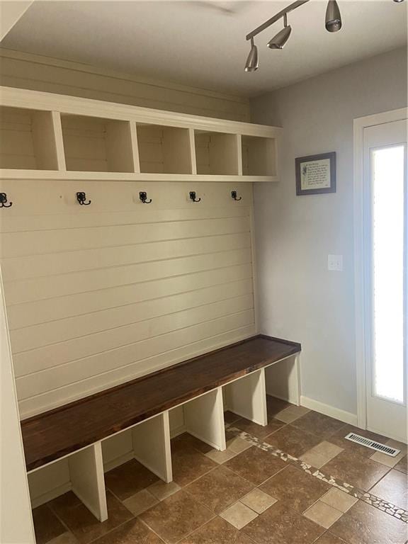 mudroom with rail lighting and dark tile patterned floors