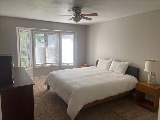 bedroom featuring ceiling fan, a textured ceiling, and dark carpet