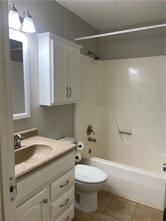 full bath featuring shower / washtub combination, tile patterned flooring, vanity, and toilet