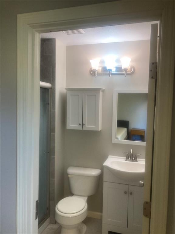 bathroom featuring a stall shower, baseboards, toilet, tile patterned floors, and vanity