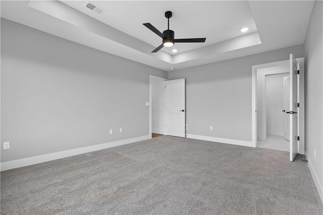 unfurnished bedroom featuring a tray ceiling, light colored carpet, and ceiling fan