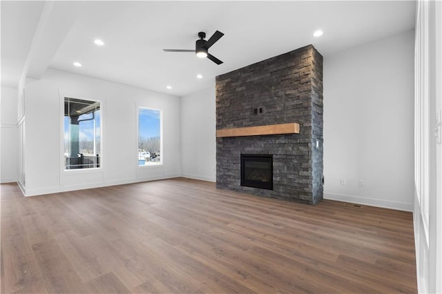 unfurnished living room with ceiling fan, a fireplace, and wood-type flooring