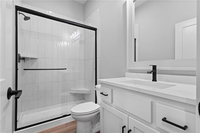 bathroom with walk in shower, vanity, toilet, and hardwood / wood-style floors