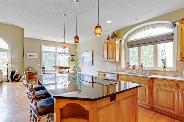 kitchen featuring a kitchen island, sink, stainless steel dishwasher, and light hardwood / wood-style flooring