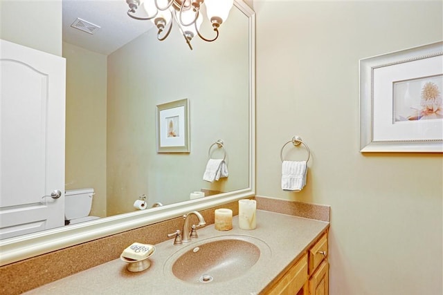 bathroom featuring vanity, toilet, and a chandelier