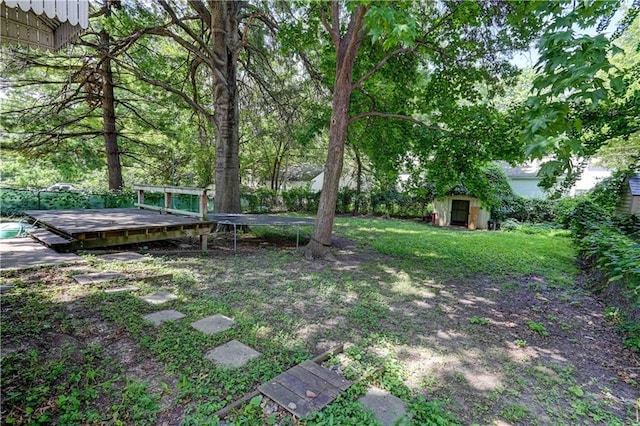 view of yard featuring a trampoline, an outbuilding, and a deck