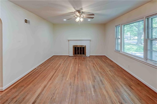 unfurnished living room with ceiling fan, a fireplace, and light hardwood / wood-style flooring