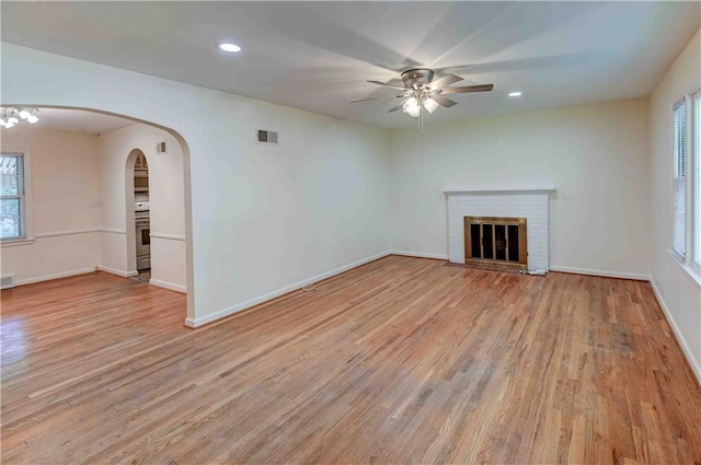 unfurnished living room featuring a fireplace, a wealth of natural light, ceiling fan, and light hardwood / wood-style floors