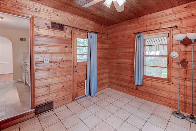 tiled spare room featuring wood walls, ceiling fan, and wooden ceiling