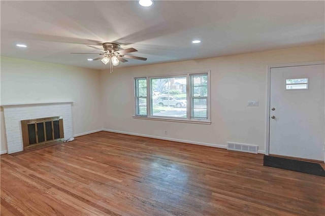 unfurnished living room with a fireplace, hardwood / wood-style flooring, and ceiling fan