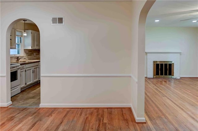 interior space featuring light wood-type flooring, a fireplace, sink, and ceiling fan