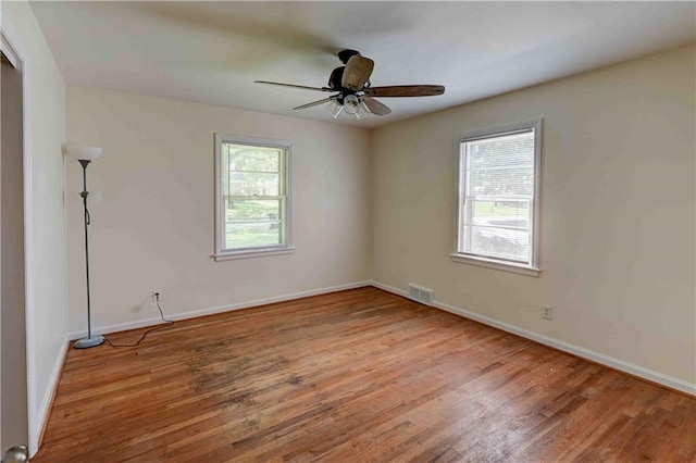 spare room featuring a wealth of natural light, ceiling fan, and hardwood / wood-style flooring