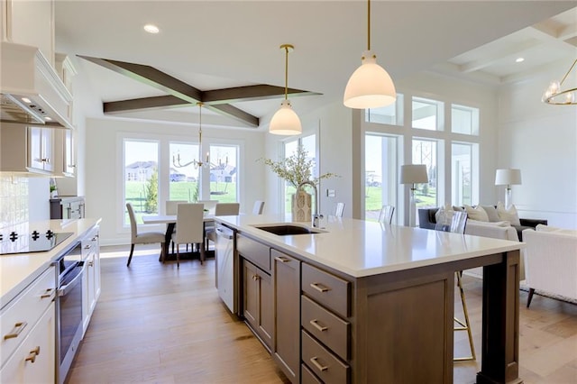 kitchen with decorative light fixtures, white cabinetry, sink, black electric cooktop, and an inviting chandelier